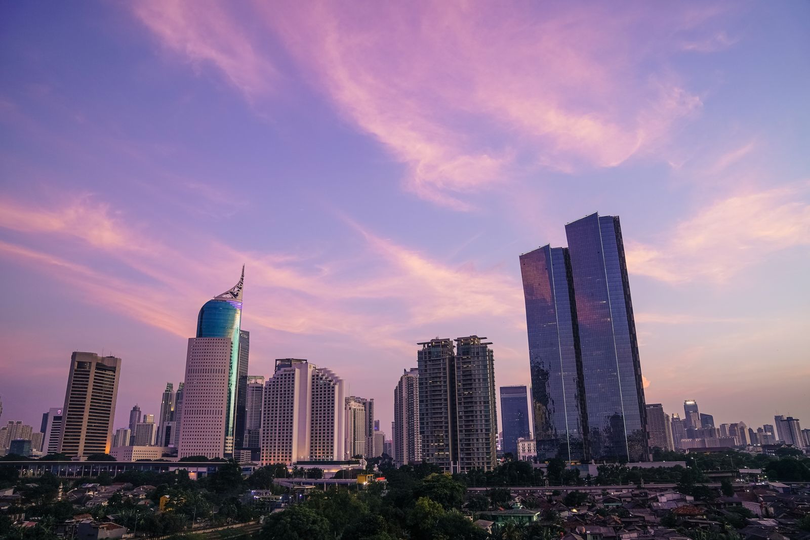 Siluet gedung-gedung tinggi Jakarta saat matahari terbenam.