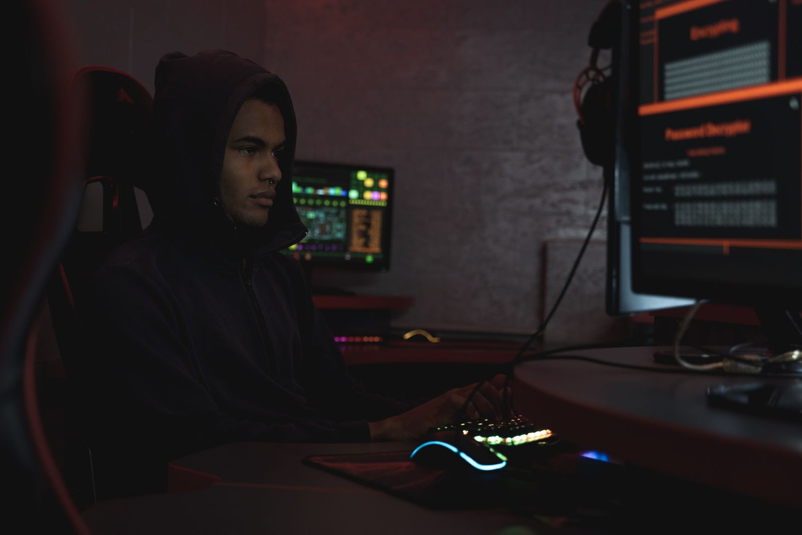 Sosok mengenakan hoodie di depan layar kode pemrograman, ilustrasi malware perbankan