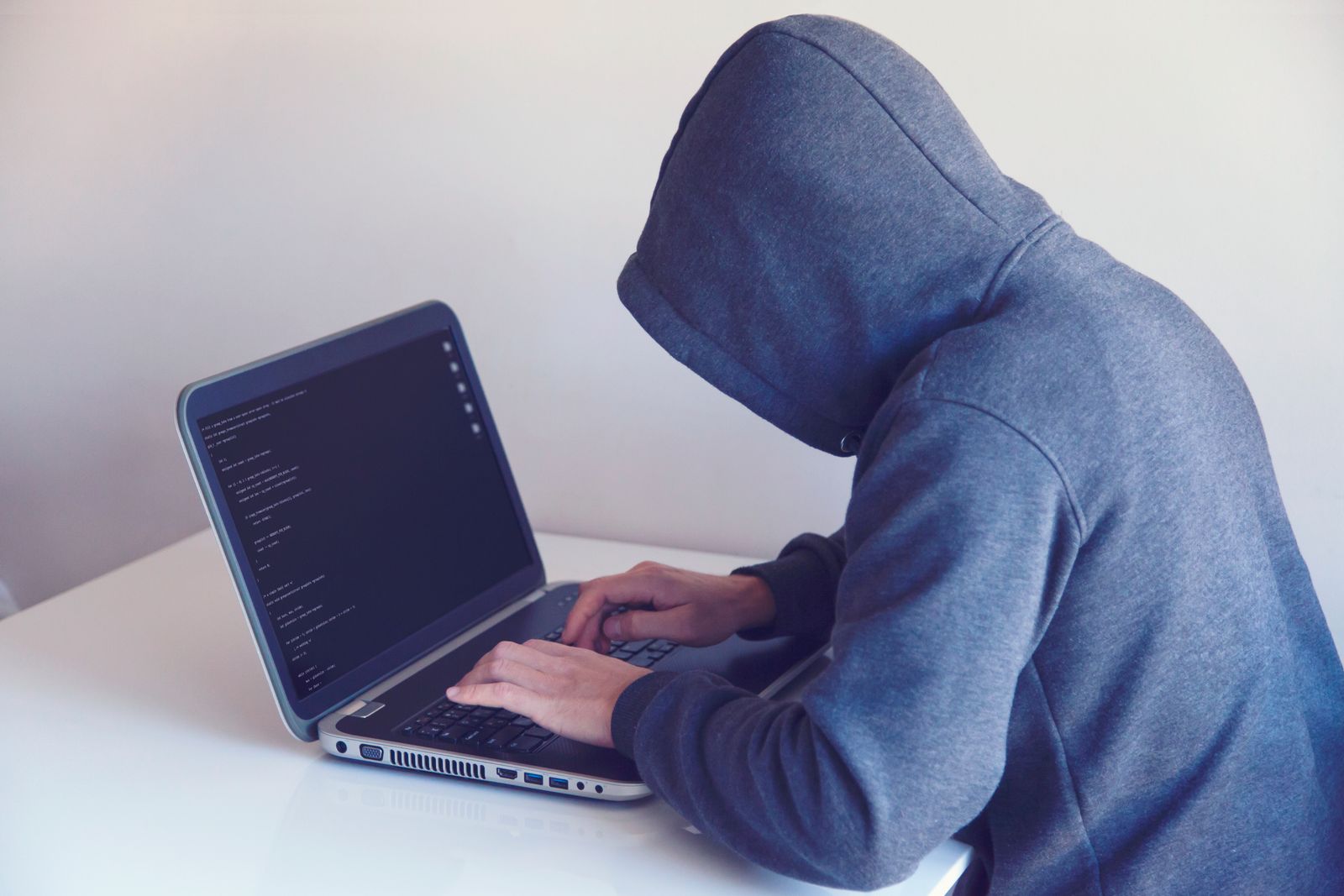 Sosok peretas berjaket hoodie di depan laptop
